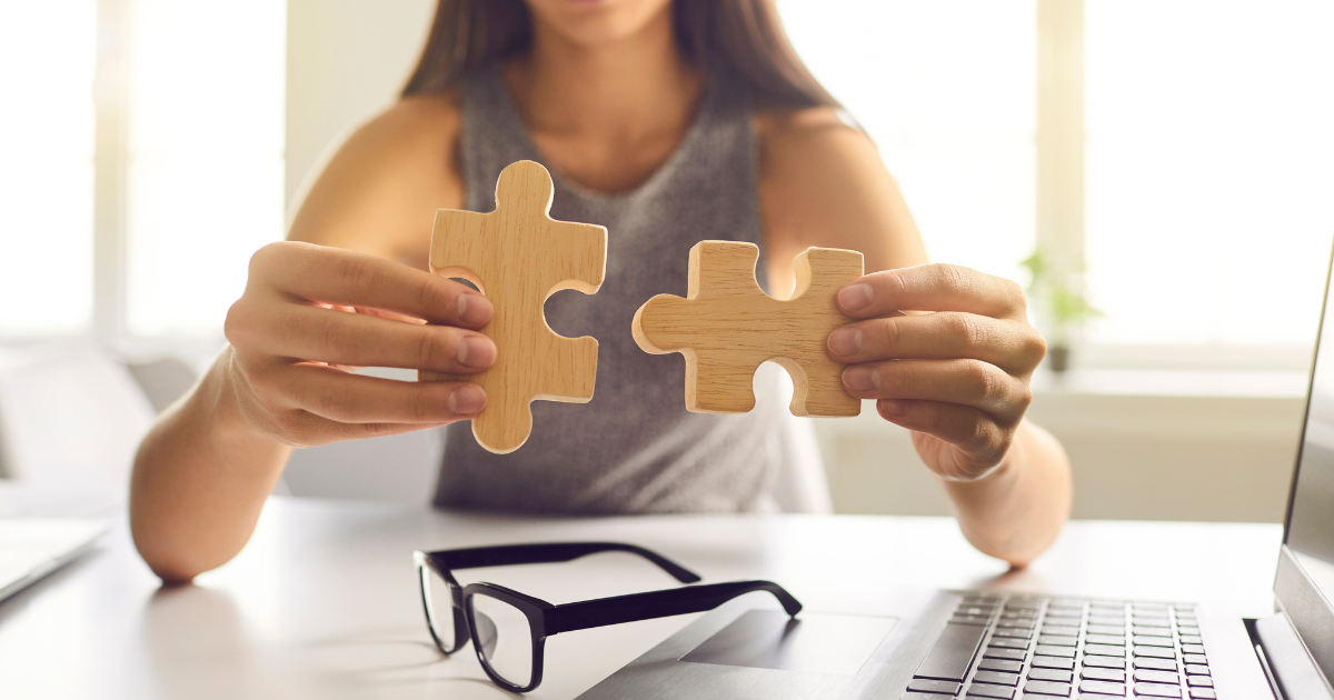 A person holding two wooden puzzle pieces near a laptop, symbolizing the seamless integration of tools like Klaviyo and Shopify for email marketing success.